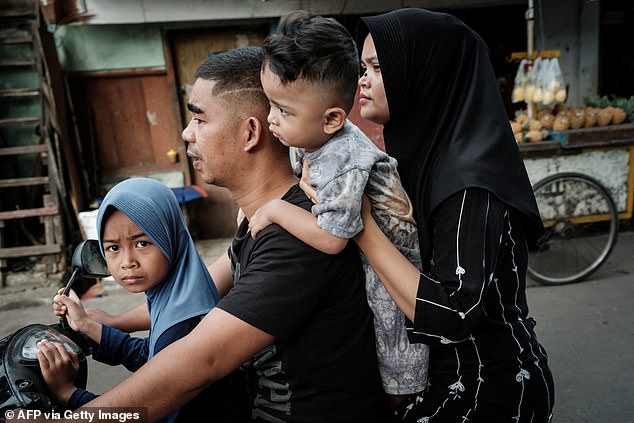 A family rides on a motor scooter in Jakarta on November 8, 2025