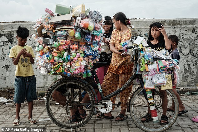 Children buy toys piled high on a bicycle next to a seawall in Cilincing, North Jakarta, on September 20, 2025