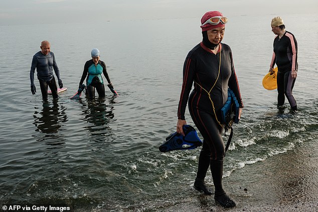 Elderly people finish their daily 40-minute swim at sea in the early morning in Jakarta on November 18, 2025