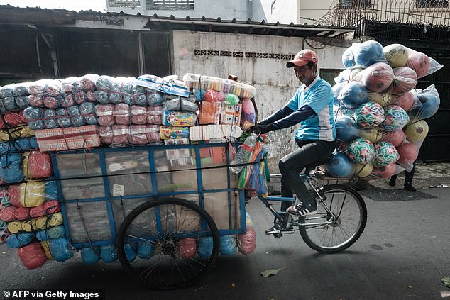 A man pedals a modified cargo tricycle loaded with goods on a street in Jakarta on May 4, 2025