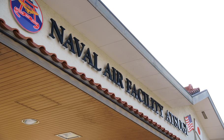 Signage for a Naval Air Facility showing ‘NAVAL AIR FACILITYATSUGI’ lettering on a beige building exterior.