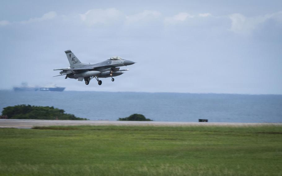 A jet takes off from a tarmac with the ocean and boats visible in the background. 