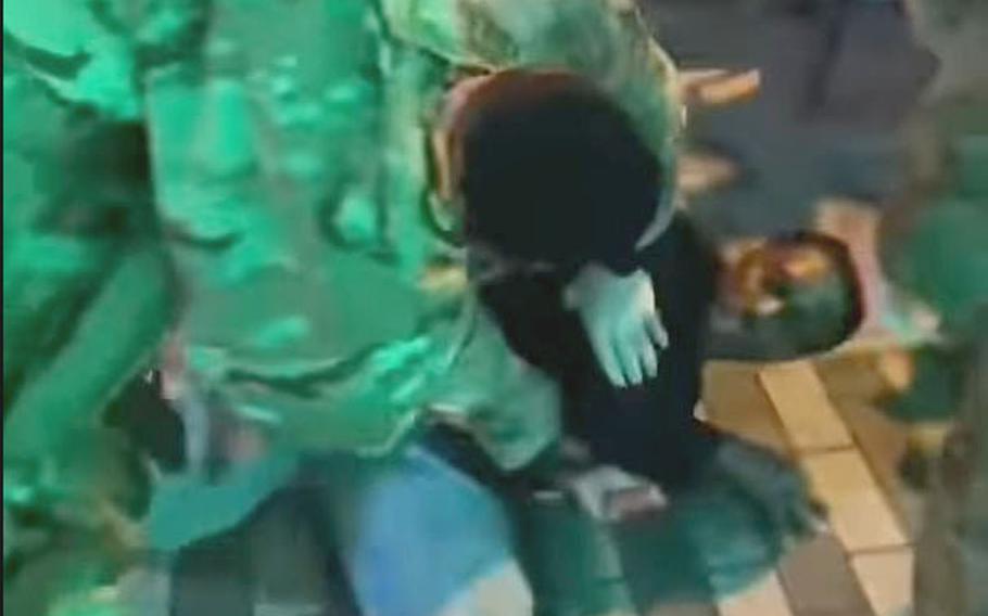  U.S. military police officers wrestle with a man.