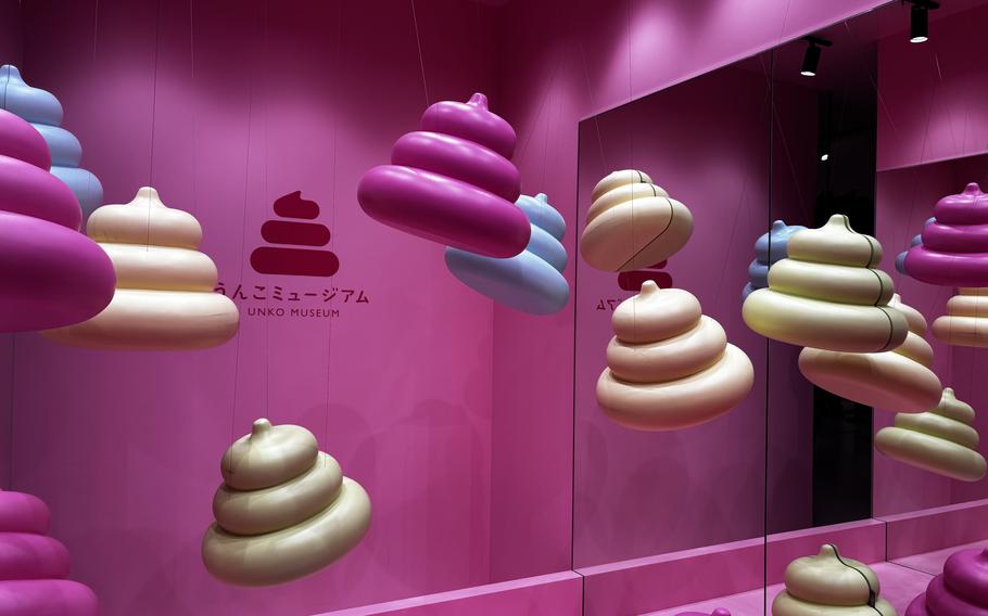 Different colored playful piles are held aloft in a bright pink room with invisible wires.