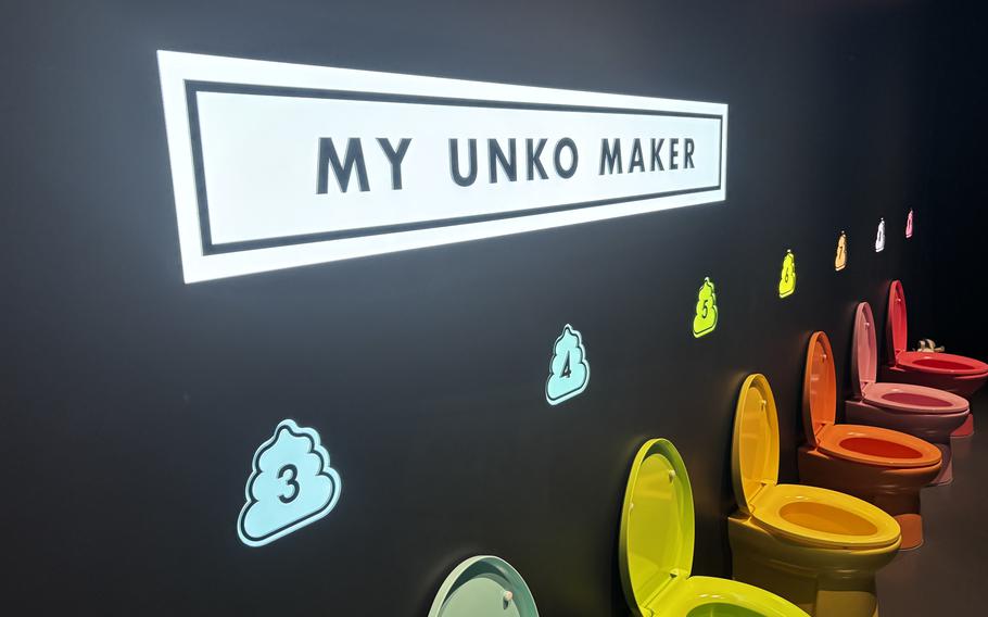A rainbow-colored row of toilets is lined up along a black wall with a sign above them that says My Unko Maker.