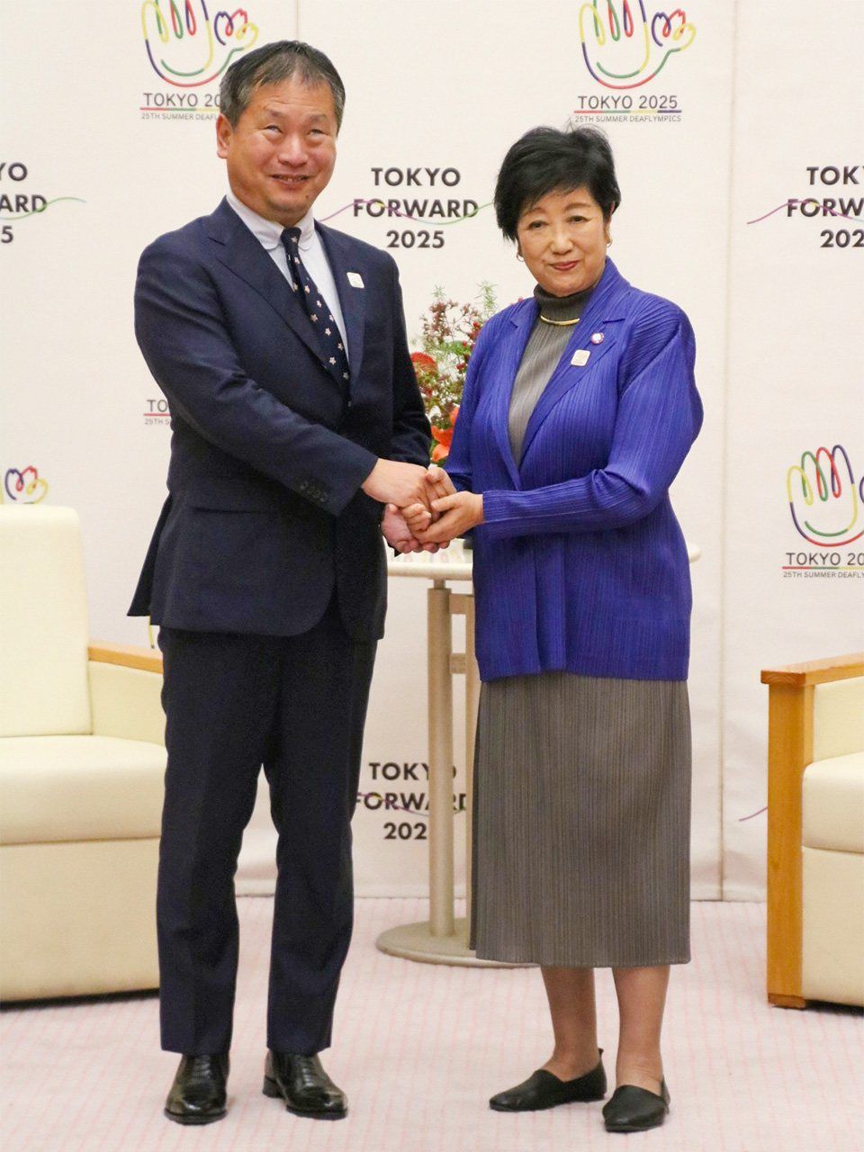 Japan Sports Agency Commissioner Kawai Jun’ichi, left, shaking hands with Tokyo Governor Koike Yuriko on October 24. (© Jiji)