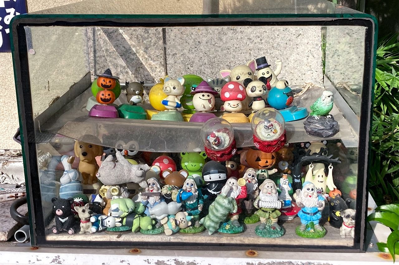 The gritty cityscape is sometimes interrupted by odd whimsical corners, like a glass case of figurines in front of a house. (© Gianni Simone)