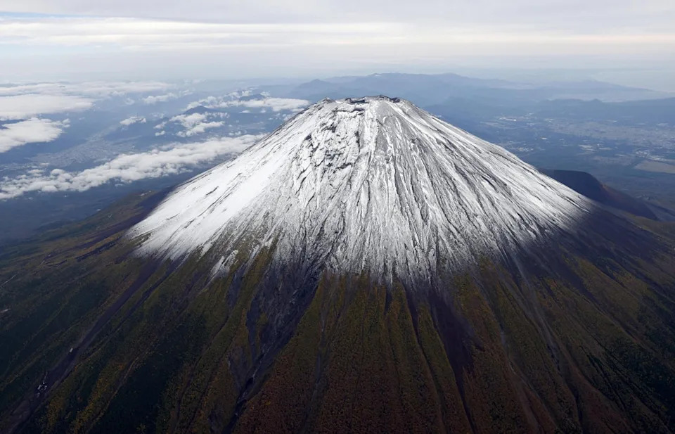 A photo taken from a helicopter shows the season’s first snowcap on Mount Fuji on 23 October 2025 (Kyodo)