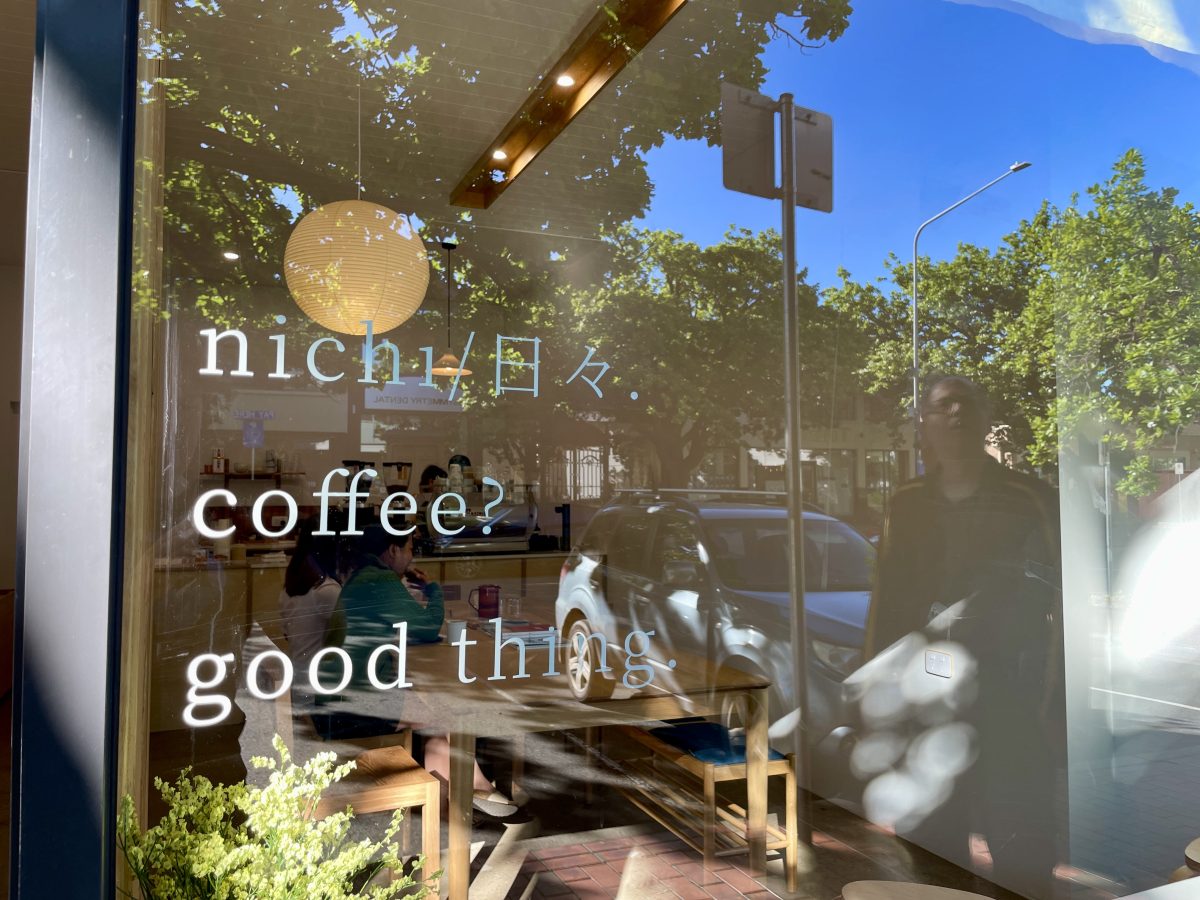 White text on a cafe window reading Nichi (followed by two Kanji characters), Coffee? Good things. 