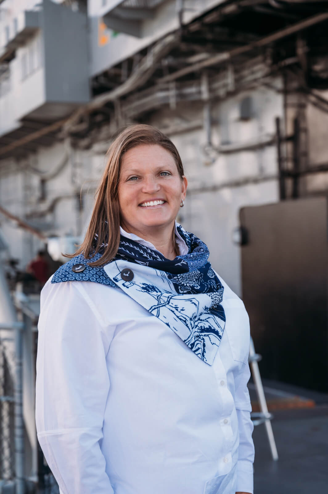 Navy spouse Jennifer Kemp wearing a white starched button-down shirt with a blue-design scarf from her business, Mottainai Creations.