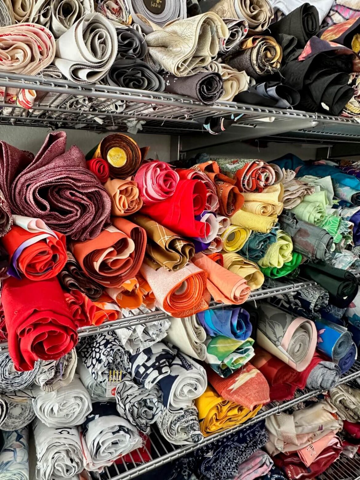 Stacks of colorful fabric rolls on a metal cabinet for Mottainai Creations, a business run by a military spouse.
