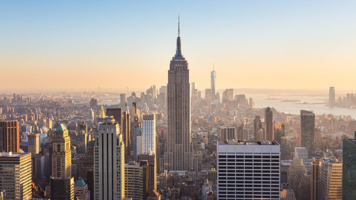 New York City. Manhattan downtown skyline with illuminated Empire State Building and skyscrapers at sunset.