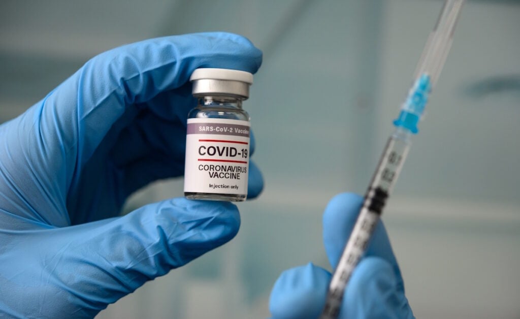 Picture of a needle and a bottle of COVID-19 vaccine