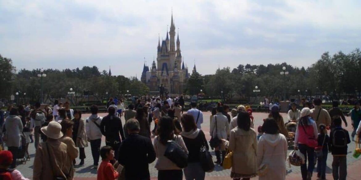 A large crowd of Disney fans walks towards Cinderella Castle at Tokyo Disneyland