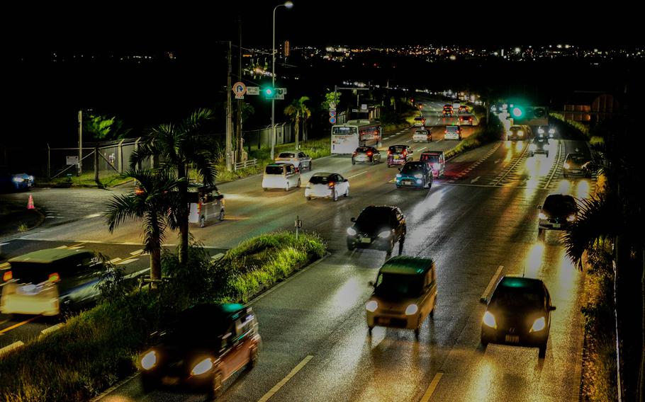 Traffic passes through an Okinawa intersection at night.