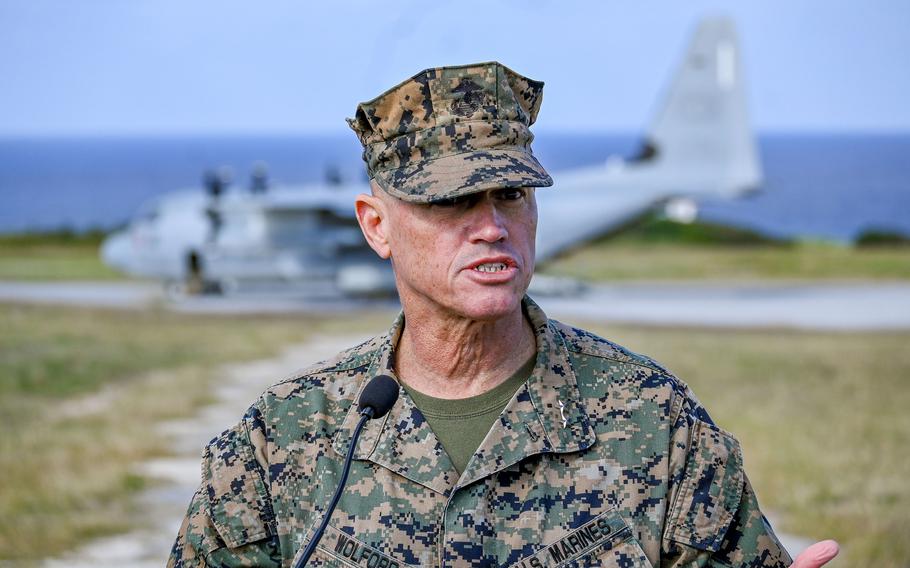 A Marine Corps Installations Pacific commander talks at a new island airfield with a plane in the background.