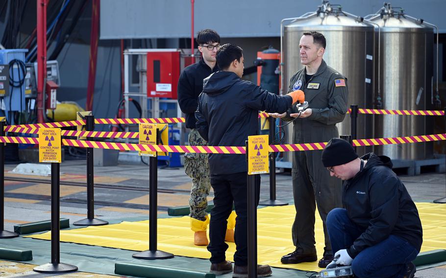 Defense Department civilians check a sailor for radiation during a drill.