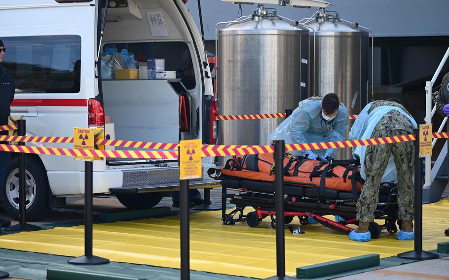 Navy corpsmen load a dummy onto an ambulance.