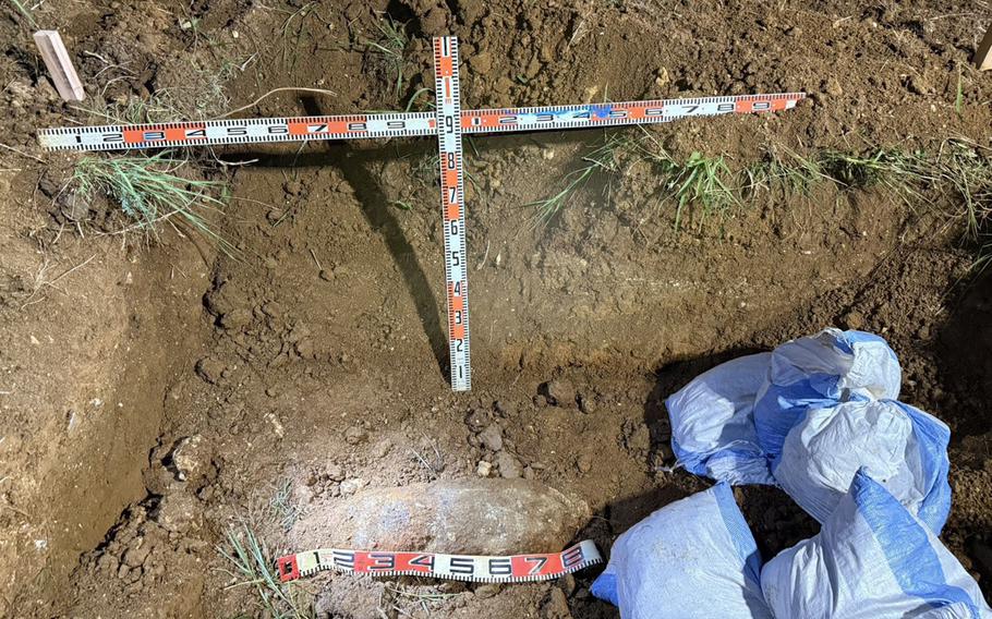An unexploded bomb is seen being uncovered in the dirt.