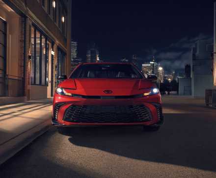 Static front-end shot of a red 2026 Toyota Camry Nightshade in the shadows.