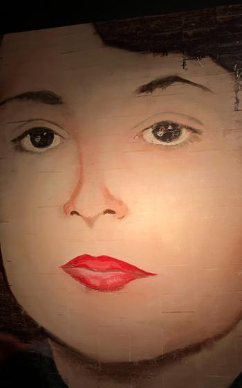 A realistic painting shows a woman’s face.