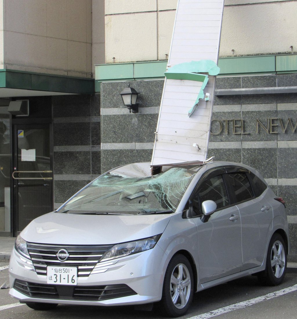 A car parked outside a hotel in Mutsu, Aomori prefecture, is damaged by a signboard that fell after a strong earthquake on Monday. Photo: Kyodo/Reuters