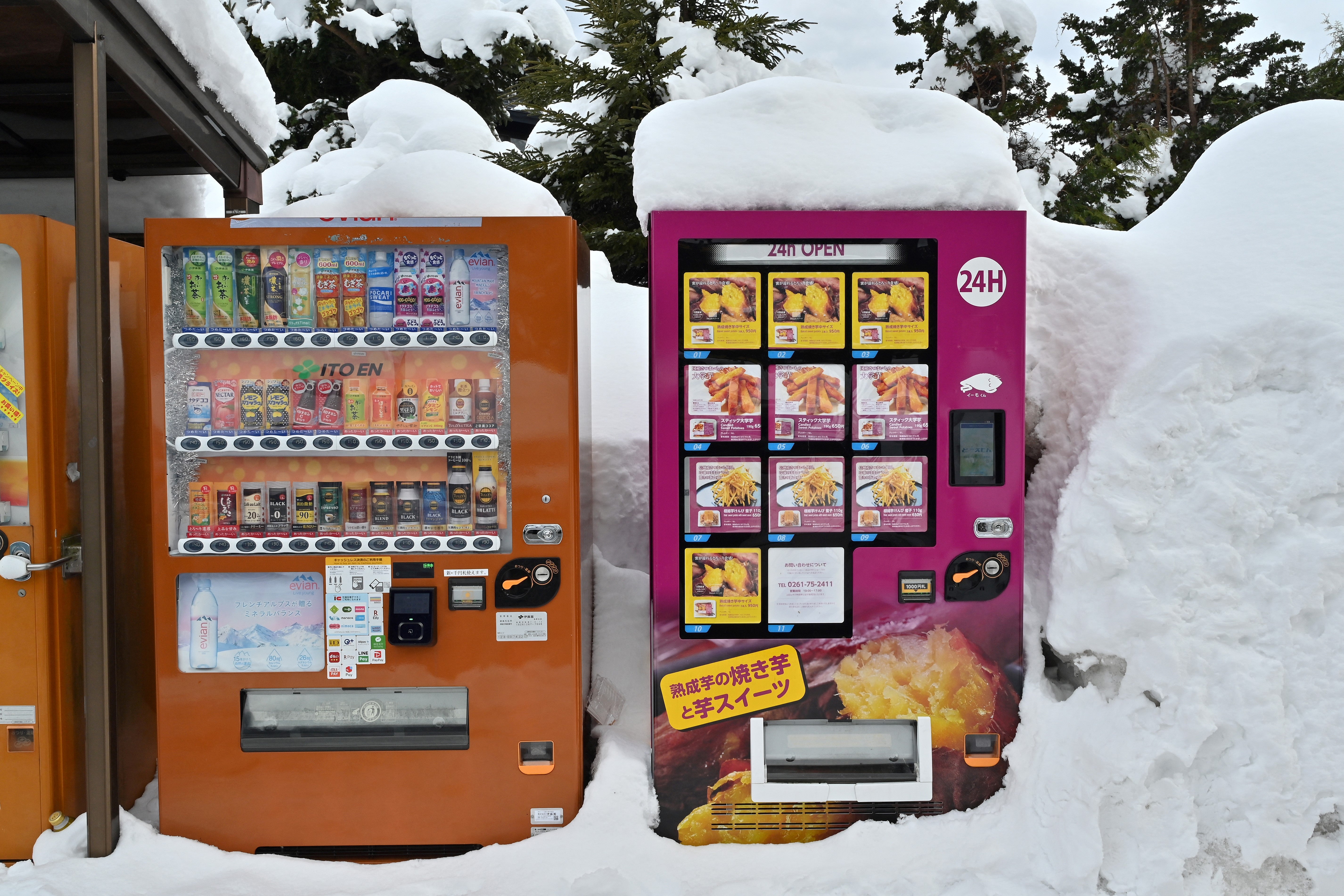Vending machines, including one for warm sweet potatoes (at R), covered in snow along a rest stop outside the ski resort town of Hakuba, Nagano prefecture. Reside