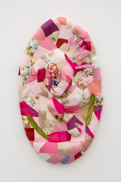 An art object made of quilted fabric in bright pink and flower patterns.