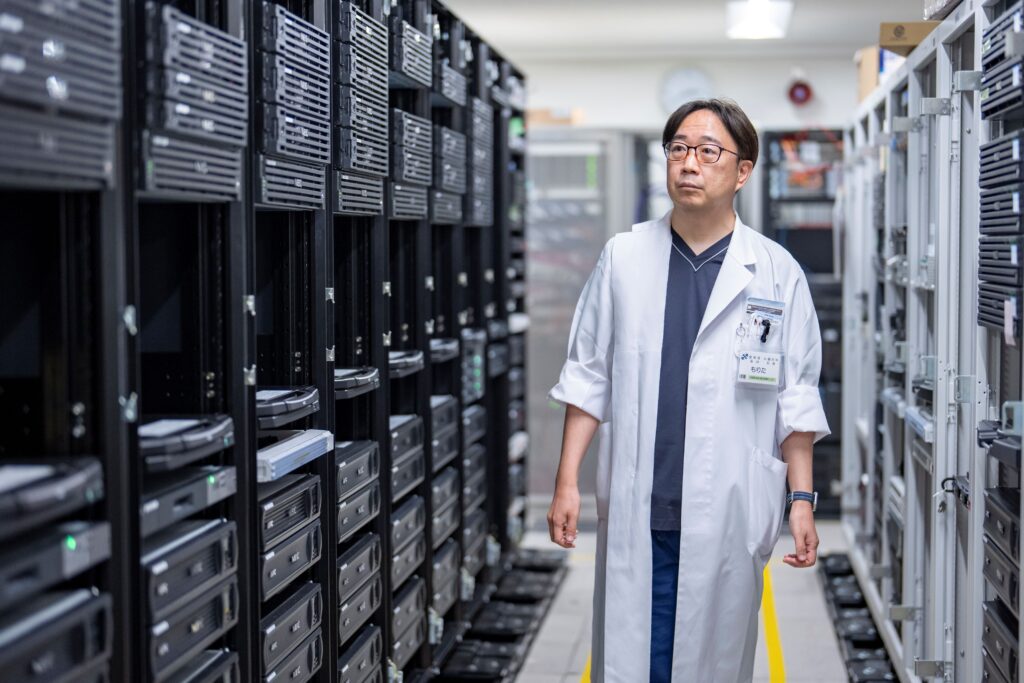 A man standing next to stacks of computer servers.