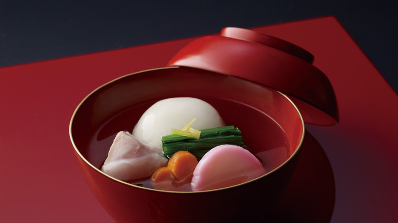 Red lacquered bowl full of ozoni or Japanese mochi soup with vegetables