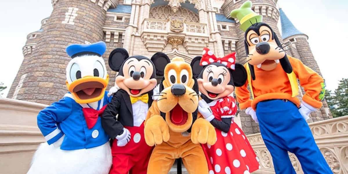 A group photo of Disney Resort characters in front of Cinderella Castle. From left to right: Donald Duck, Mickey Mouse, Pluto, Minnie Mouse, and Goofy.