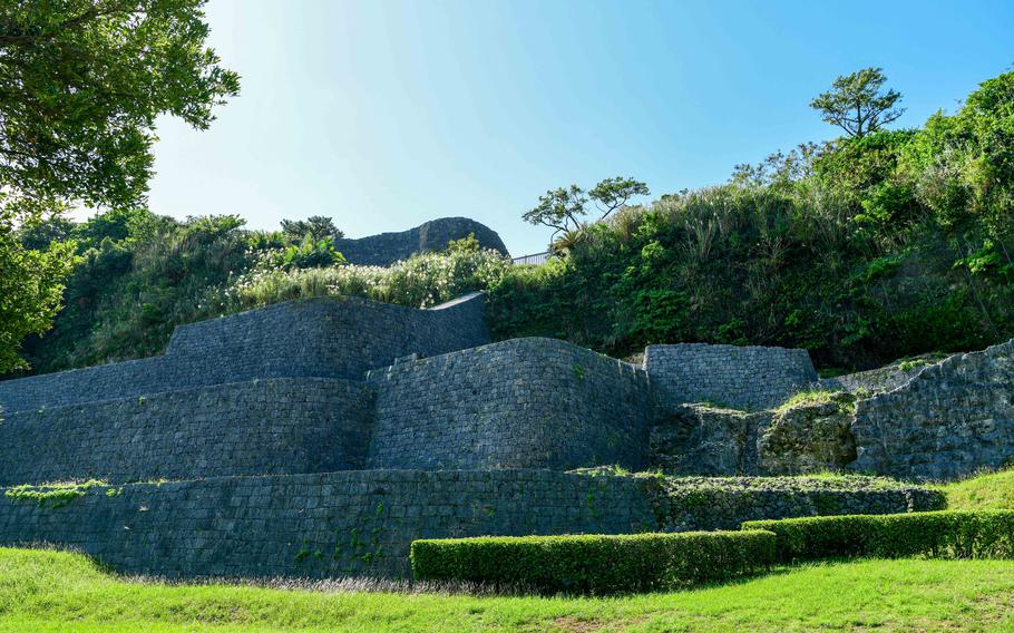 Castle ruins are in shadow with greenery in the foreground.