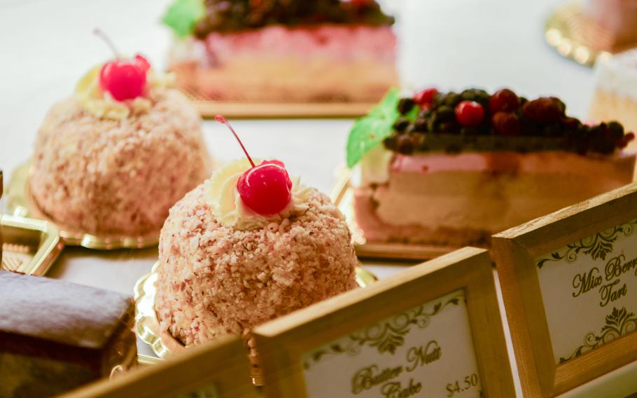Slices of cake sit on a table behind identifying signs.