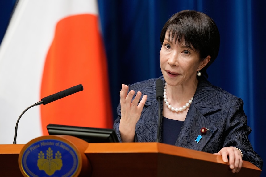 A woman gestures as she speaks into a microphone at a lectern