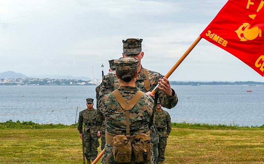 A major receives the command guidon during a waterfront ceremony.