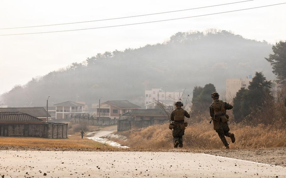 Marines run toward a building while conducting mock platoon attacks.