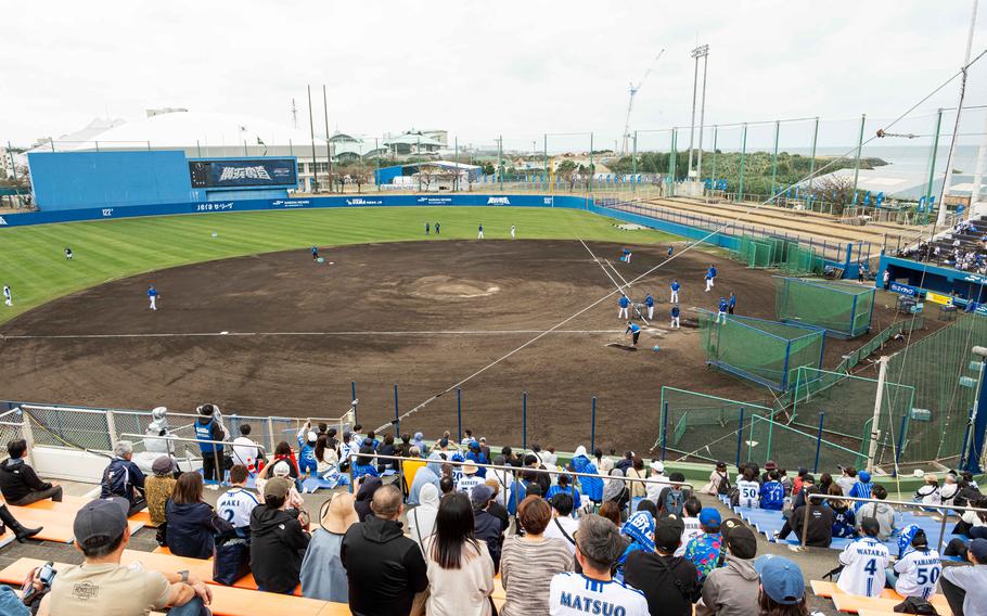 Yokohama DeNA BayStars players practicing during spring training; there are many audience at the stadium.