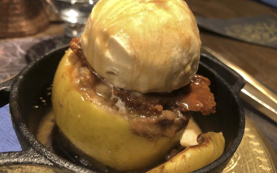 A seasonal Granny Smith baked apple dessert, featuring a hot, baked green apple stuffed with walnuts, raisins, crumble, and Ugandan vanilla custard cream,  topped off with gelato and caramel sauce at Carvaan in Shibuya, Tokyo. 