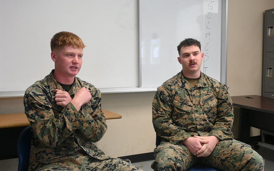 Two U.S. servicemembers sit and speak in a room in Okinawa, Japan.