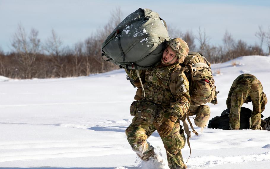 A service member carries heavy gear during training.