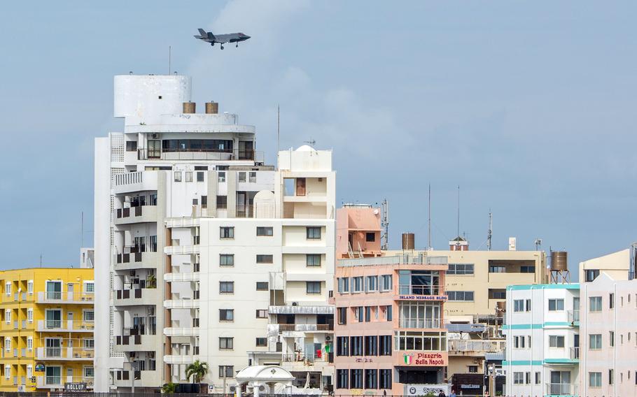 A military jet flies over residential buildings in Okinawa.