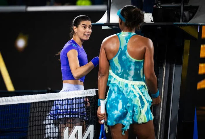 Sorana Cirstea and Naomi Osaka in athletic attire having an animated discussion at the net during a match