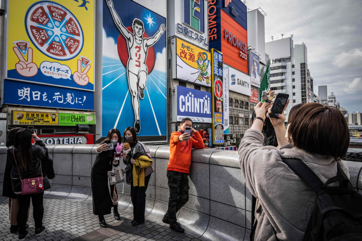 People take photographs in front of the Dotonbori Glico Sign in Osaka on Dec. 1, 2022. [AFP/YONHAP]