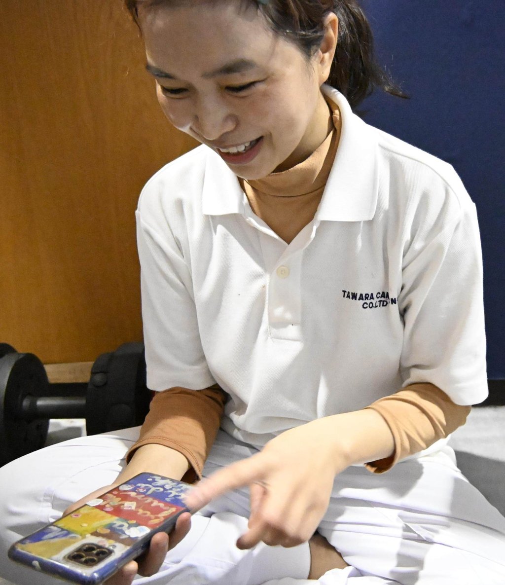 Ho Thi Thuy Nhung shows words written by her son on her smartphone case in her dormitory at Tawara Canning. Photo: Kyodo