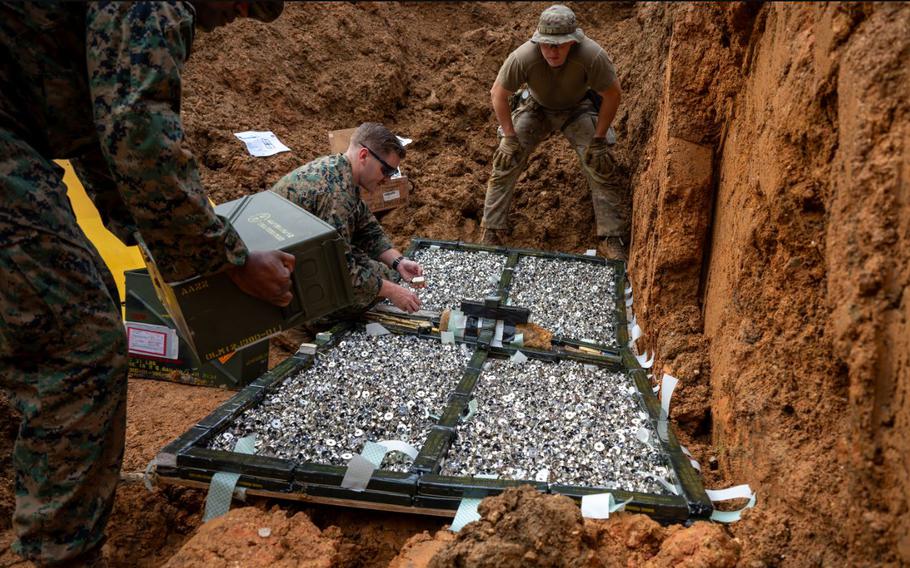 U.S. Air Force Senior Airman Jack Sanderson, center, 18th Civil Engineer Squadron explosive ordnance disposal team member, and U.S. Marines from the 3D Intelligence Battalion prepare unusable Code H munitions for a controlled detonation at Kadena Air Base.