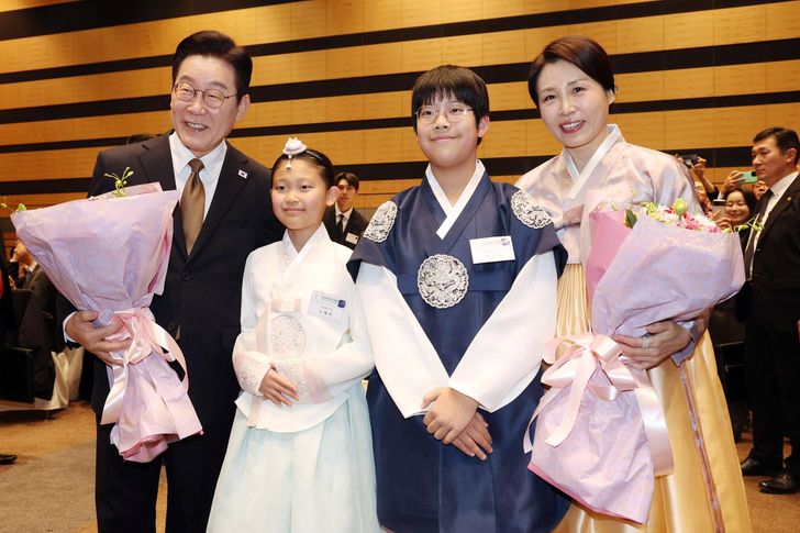 President Lee Jae Myung and first lady Kim Hea Kyung take a commemorative photo with children at a meeting with members of the Korean community residing in the Kansai region at a venue in Nara prefecture, Japan, Wednesday. Yonhap