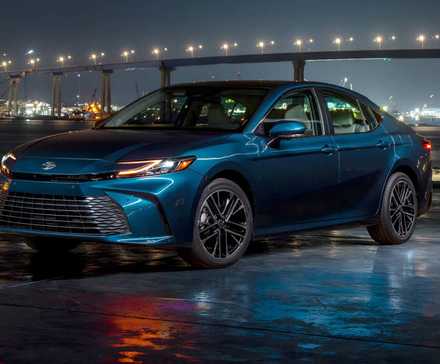 2025 Toyota Camry XLE in blue posing in front of bridge