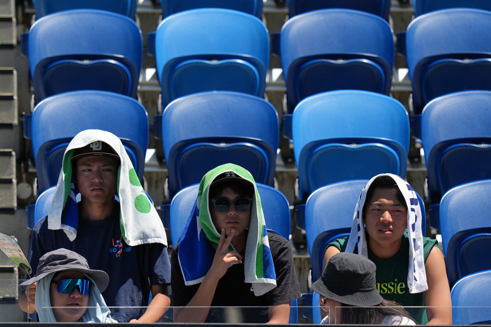 Three spectators with towels over their heads at Australian Open.