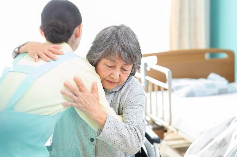 Nursing home worker helping woman out of wheelchair