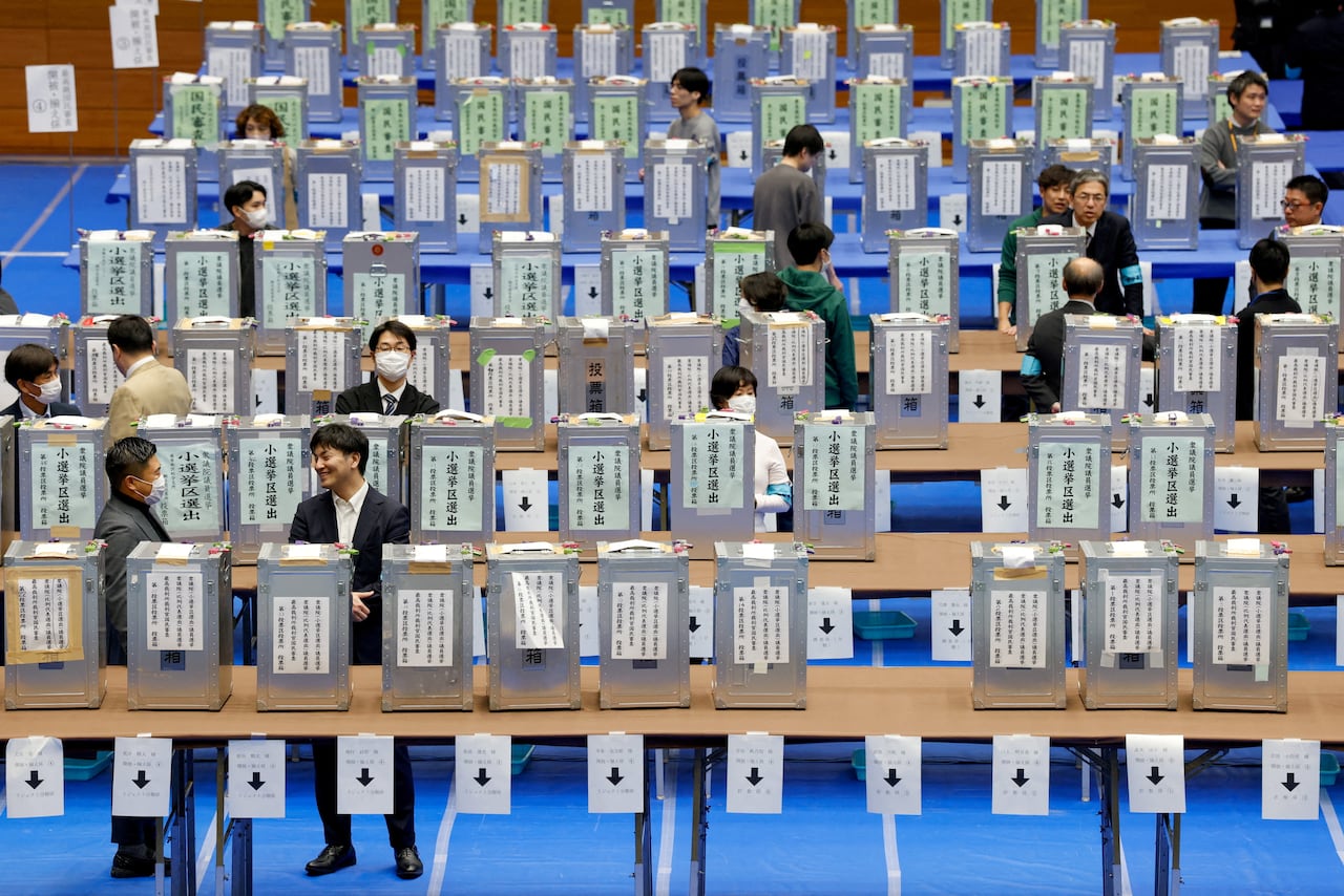 Election officials stand next to ballot boxes at a counting centre.